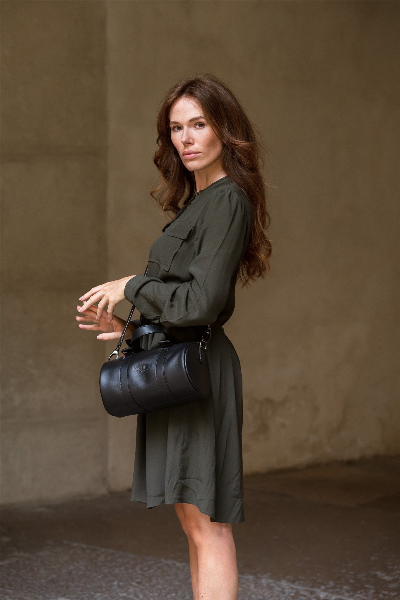 sac bowling femme cuir noir porté par une femme en robe kaki
