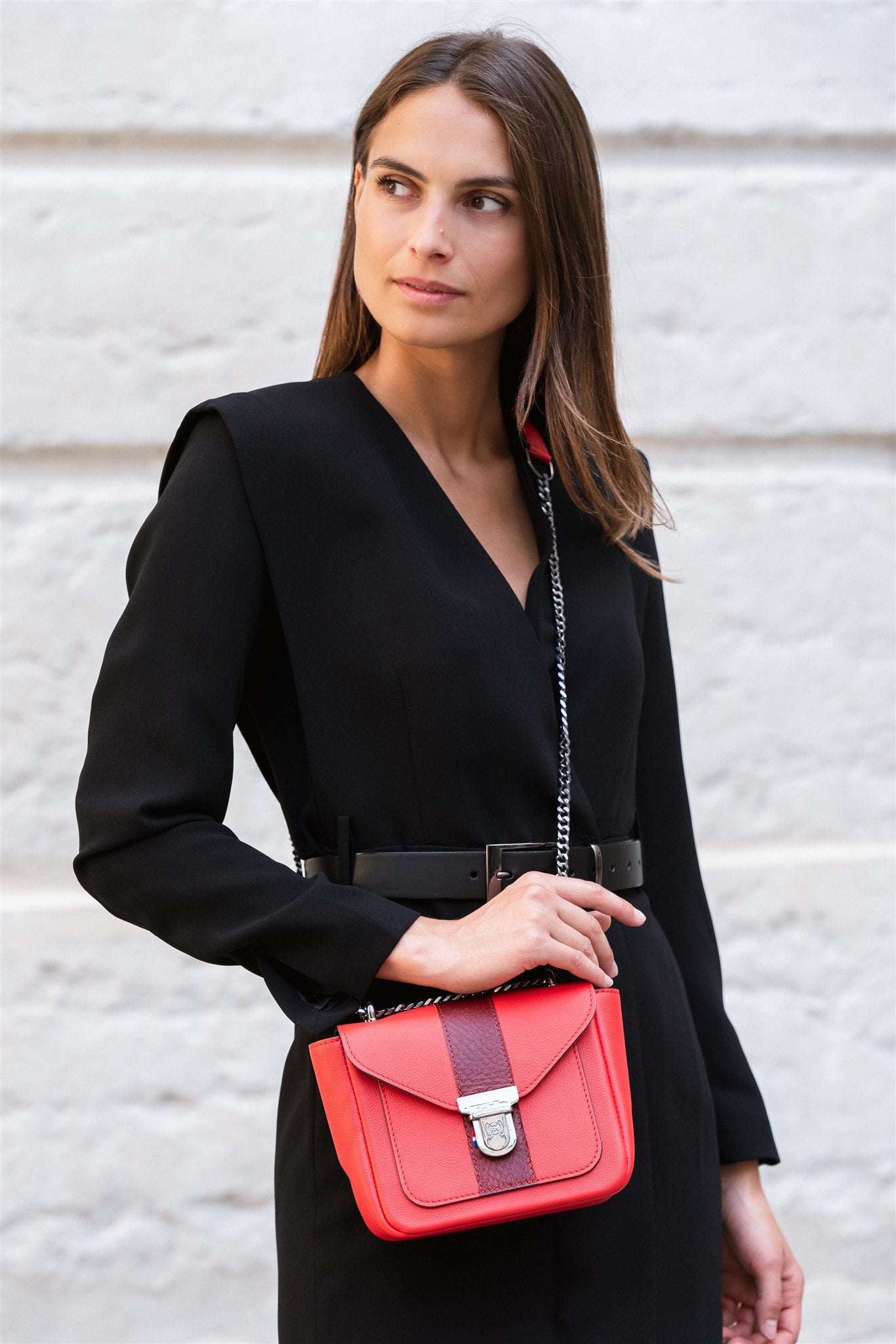 sac bandouilère cuir rouge porté par une femme en robe noir