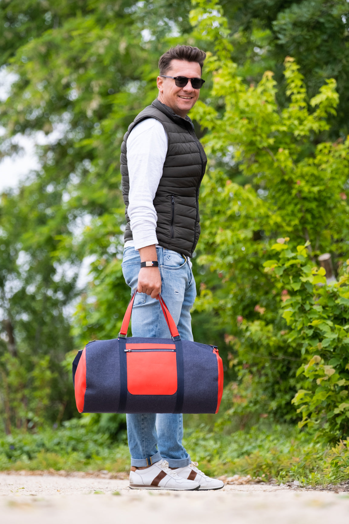 Homme avec un sac de voyage cuir et jeans rouge